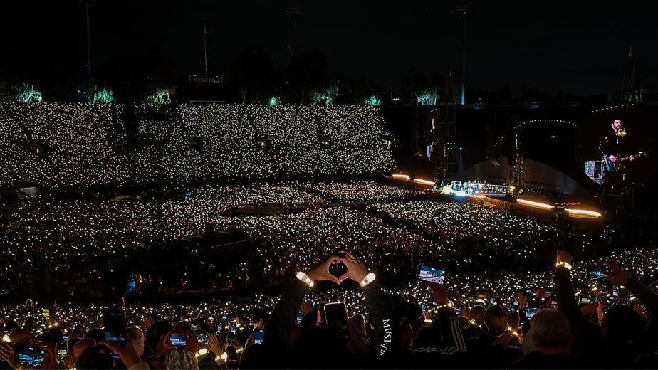 A fan displaying a hand heart towards Coldplay during the band's performance of "Yellow."